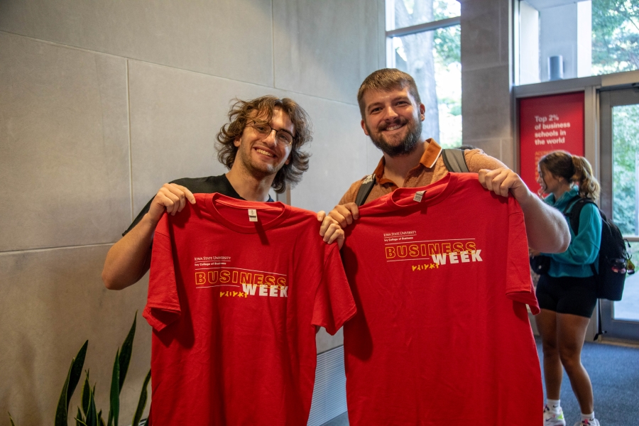 Two male students holding up Business Week 2023 t-shirts.