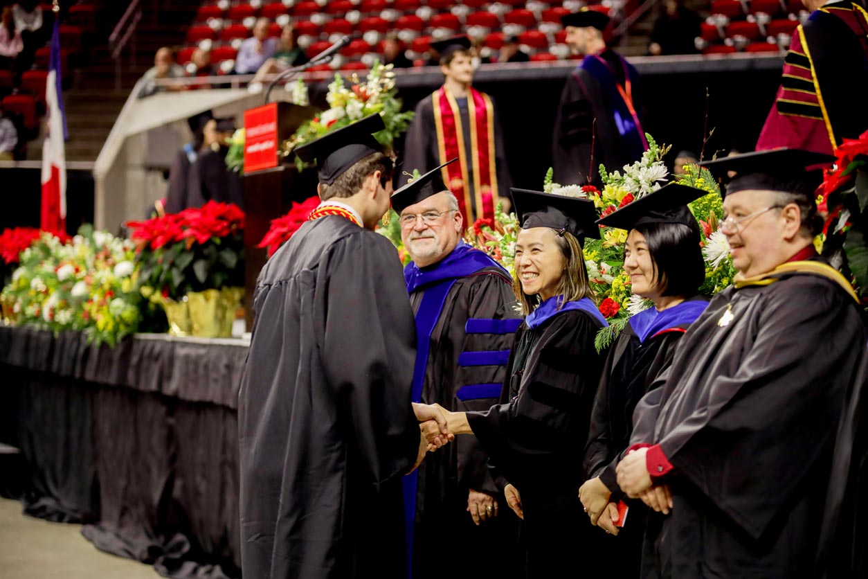 Group-of-faculty-shaking-hands-with-student graduate