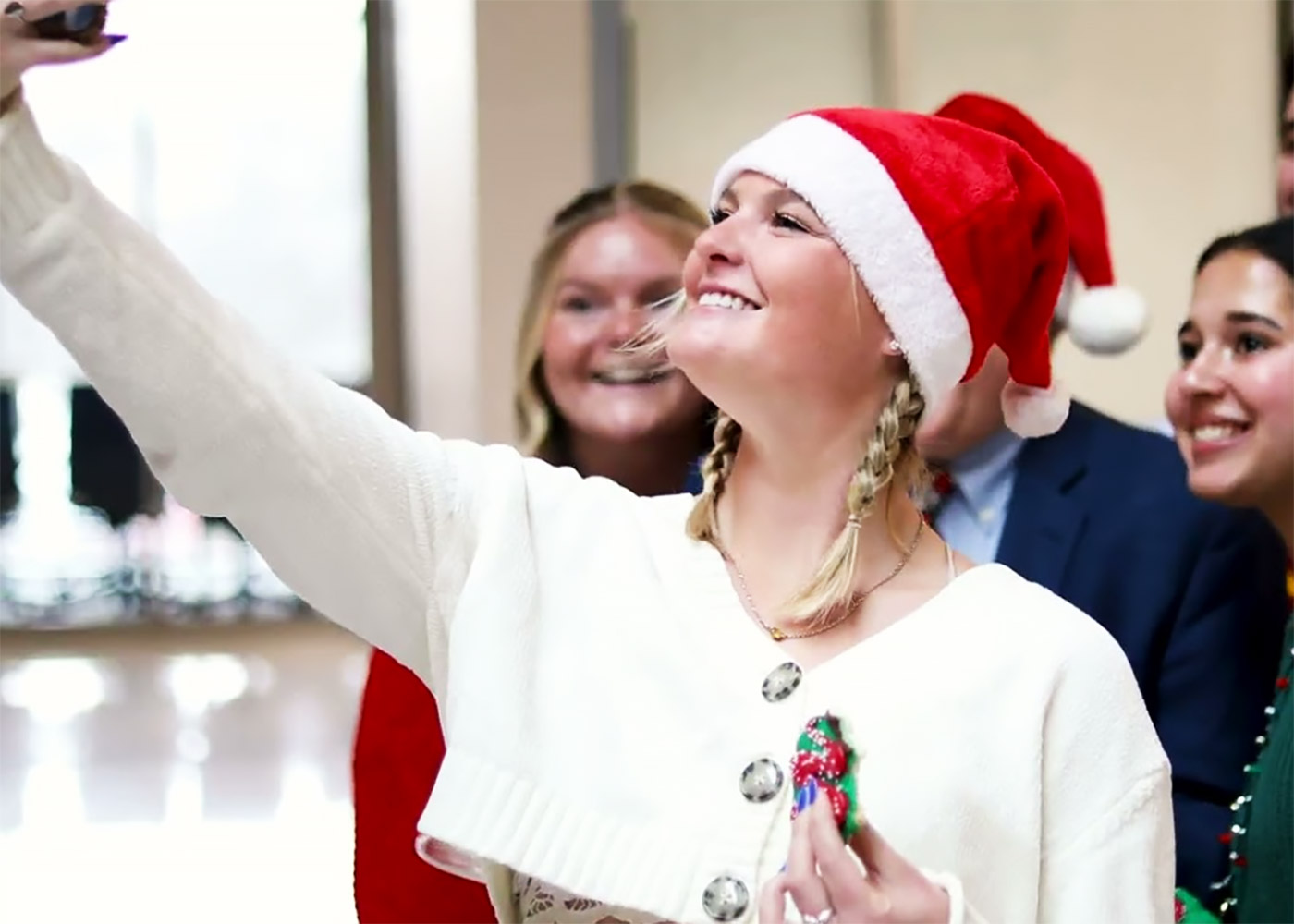 female student with snanta hat taking a selfie surrounded by friends.