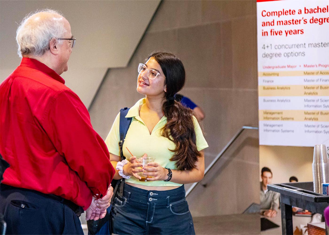 Student and dean discussing concurrent degree programs with banner in the background.