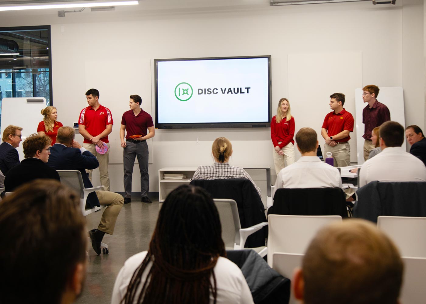 Group of students pitch their product using a detailed PowerPoint graphic titled Disc Vault