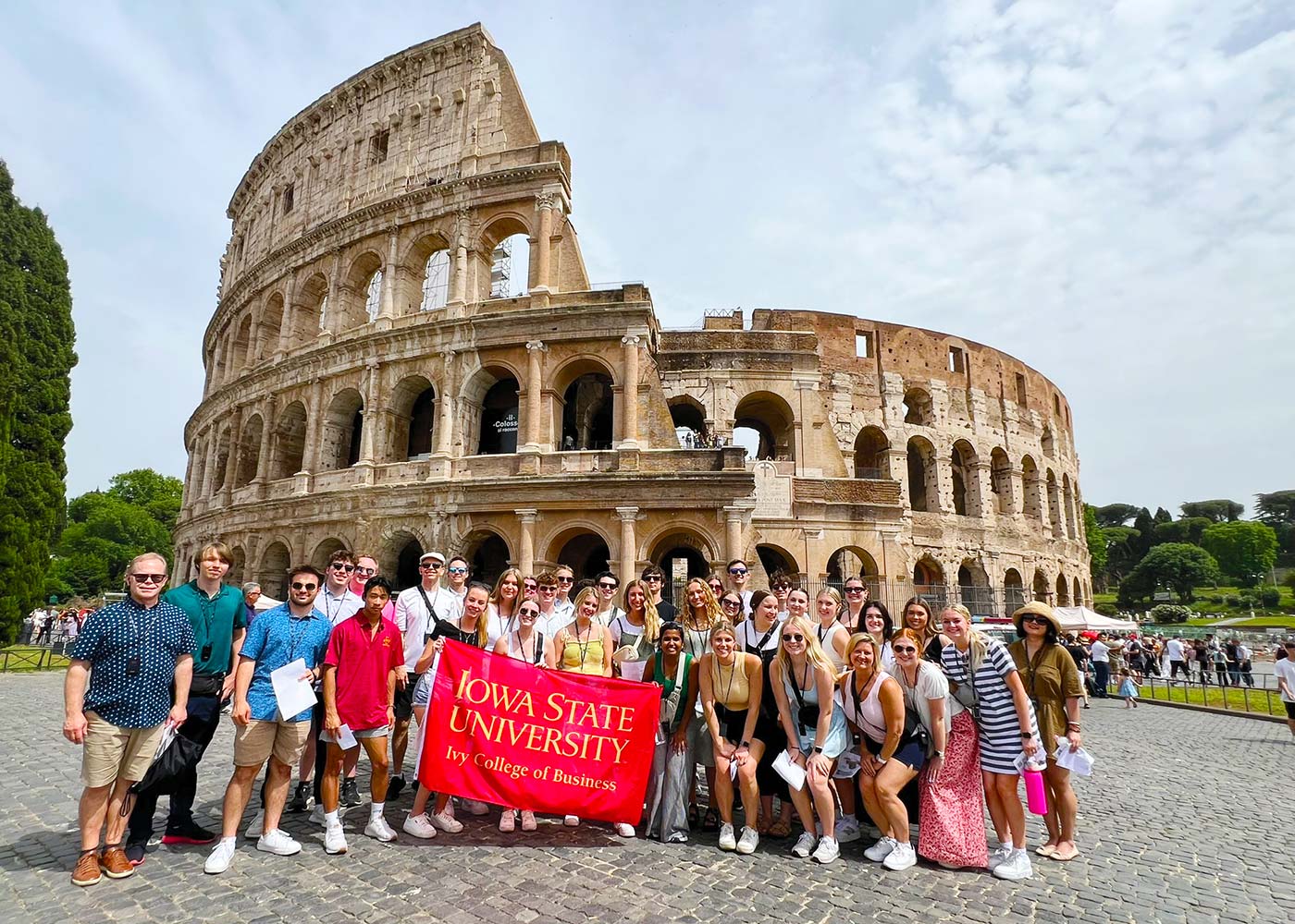 Group of Ivy student and faculty pose in front of the Roman Colosseum.